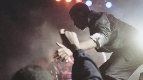 A man on stage performs while a crowd cheers on. 