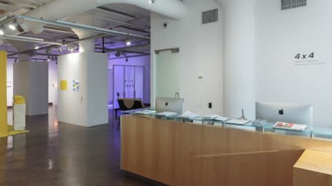 Photo from front of SVA Chelsea Gallery showing the front desk and an exhibition space.