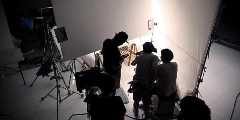 Group of people on a filming set with lights.