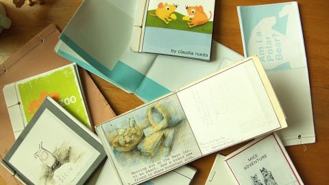 A table with story books spread out open to pages that reveal cute illustrations of mice and other animals