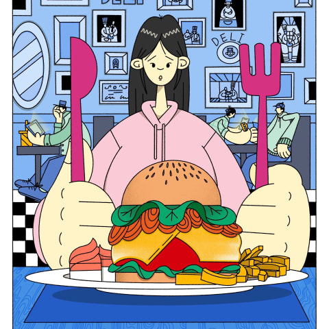 A girl with a big purple knife and fork surveys the food and hamburger in front of her. 