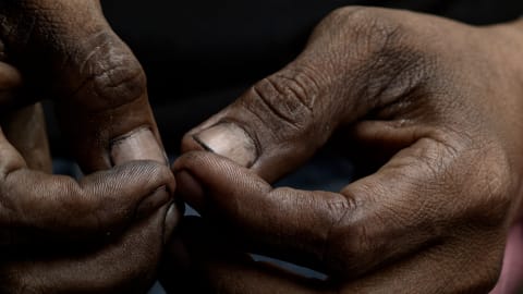 Still from The Mechanics short film, a photo of a pair of curled hands, with some dirt around the fingernails.