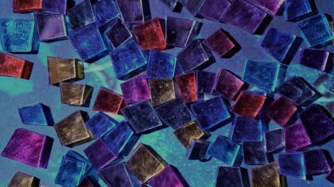 Photo of colorful glass tiles, shaped in varying jagged squares, against a blue-hued backdrop.