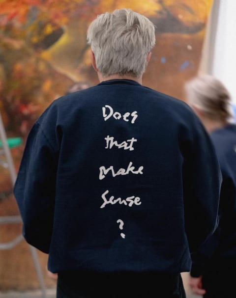A man in a sweatshirt from behind that reads "Does that make sense" 