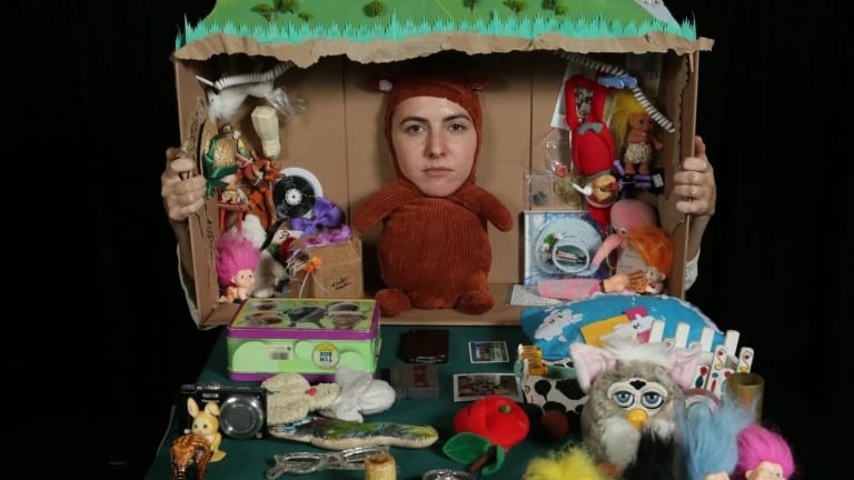 Face of Shayna Strype on teddy bear body in tableau with cardboard box and toys