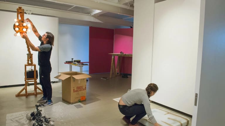 Two students installing artwork for exhibition 