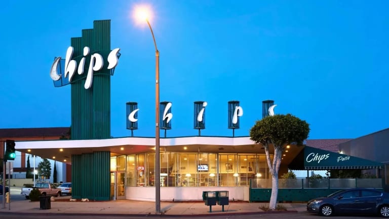 A photograph of the exterior of the Chips Restaurant in Los Angeles, CA, which features a tall, dark green column that bears the name of the restaurant in white letters, and a single story dinning room. 