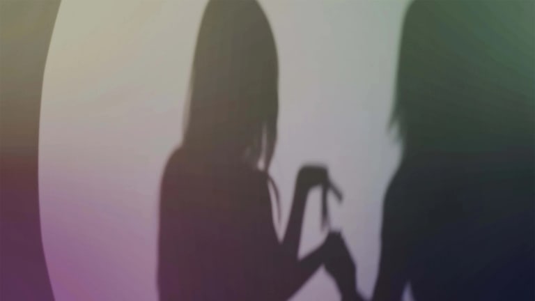 Two shadows of female figures dancing.