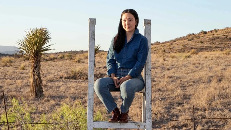 Image of Daisy Nam sitting on a fence in the desert