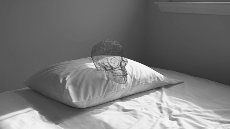Image of pillow on a bed with a skull on the pillow
