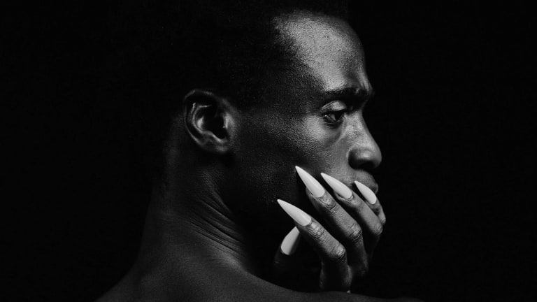 Black and White portrait of man resting styled nails on neck.