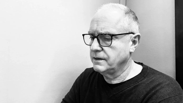 black and white image of an old man in black glasses and a black t shirt 