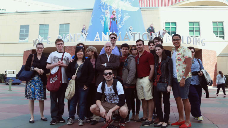 A group of students smiling outside of the Walt Disney Animation Studio entrance.