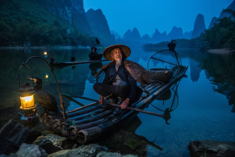 men on boats in a river with birds