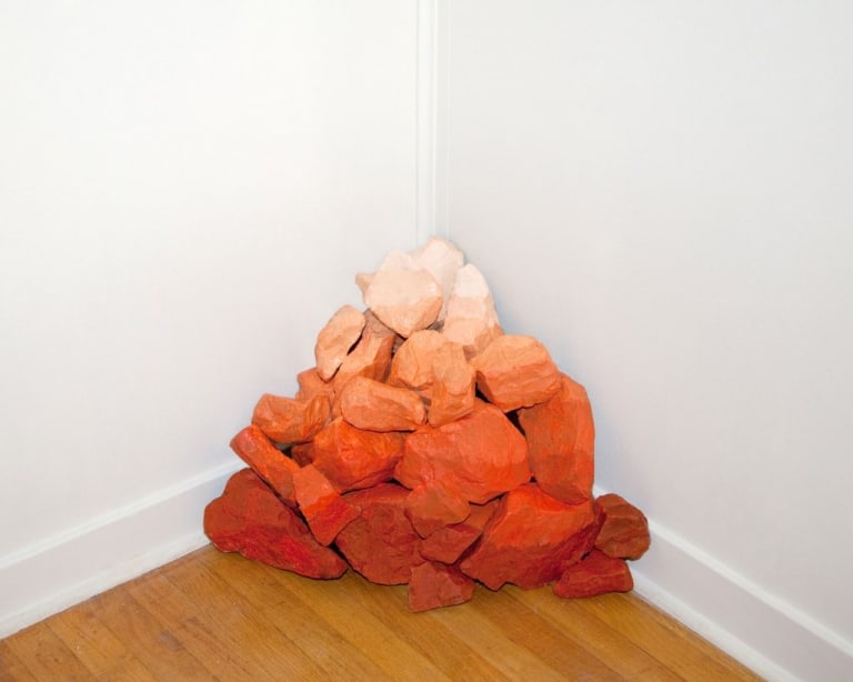 The pile of rocks in the corner fade from light orange and cream to dark orange and red.