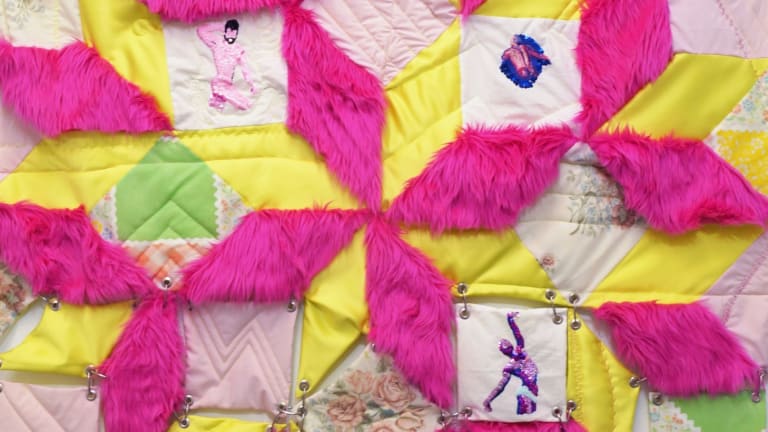 A patterned quilt with yellow and fuzzy hot pink patches, old-fashioned floral patterned patches, and sequined male dancer decals