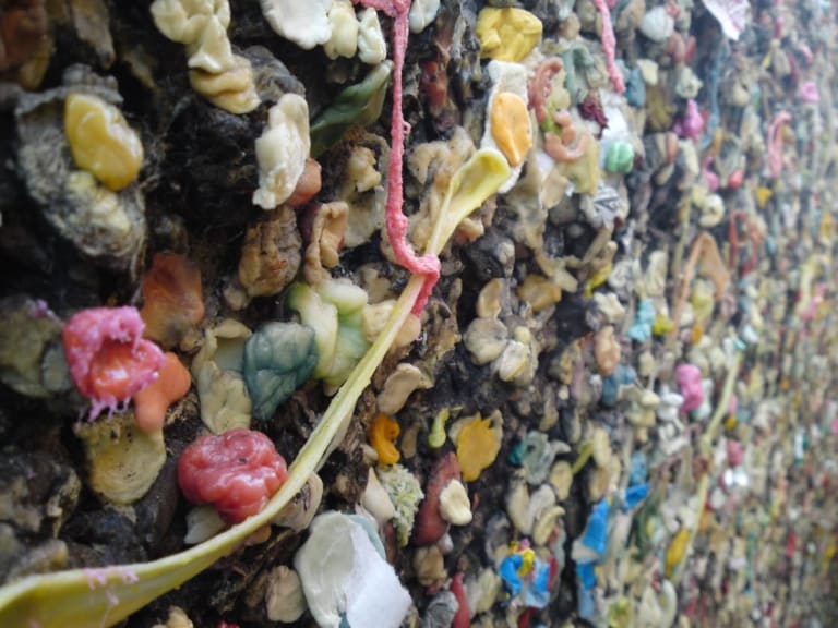 A bunch of chewed up gum  of varying colors stuck to a wall