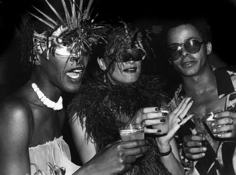 A black and white photograph of three people posing together in masquerade masks