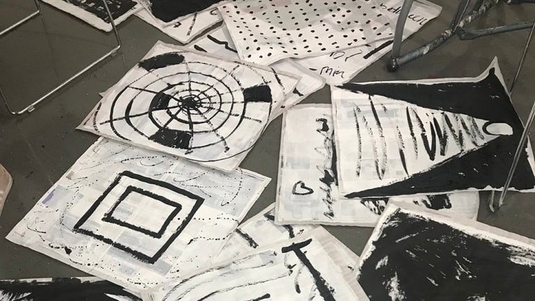 A photograph of papers with ink drawings spread across a floor