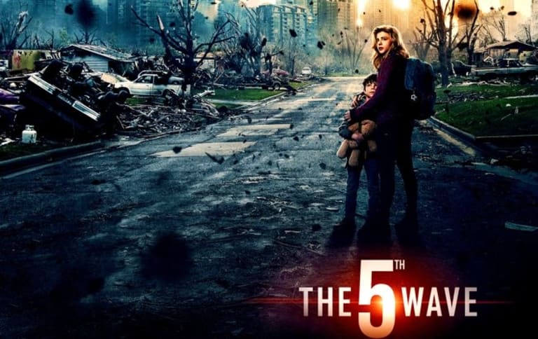 An advertisement for The 5th Wave depicting a young woman holding a small boy close to her body in front of various rubble and destruction.