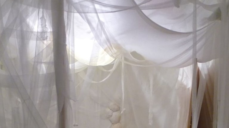 White drapes and curtains cover the interior of a room.