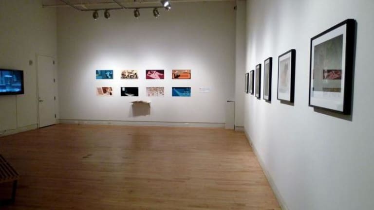 A large room with hardwood floor and various artworks on white walls.