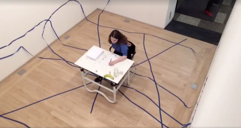 Woman at a desk with blue ribbons around the room, viewed from above.