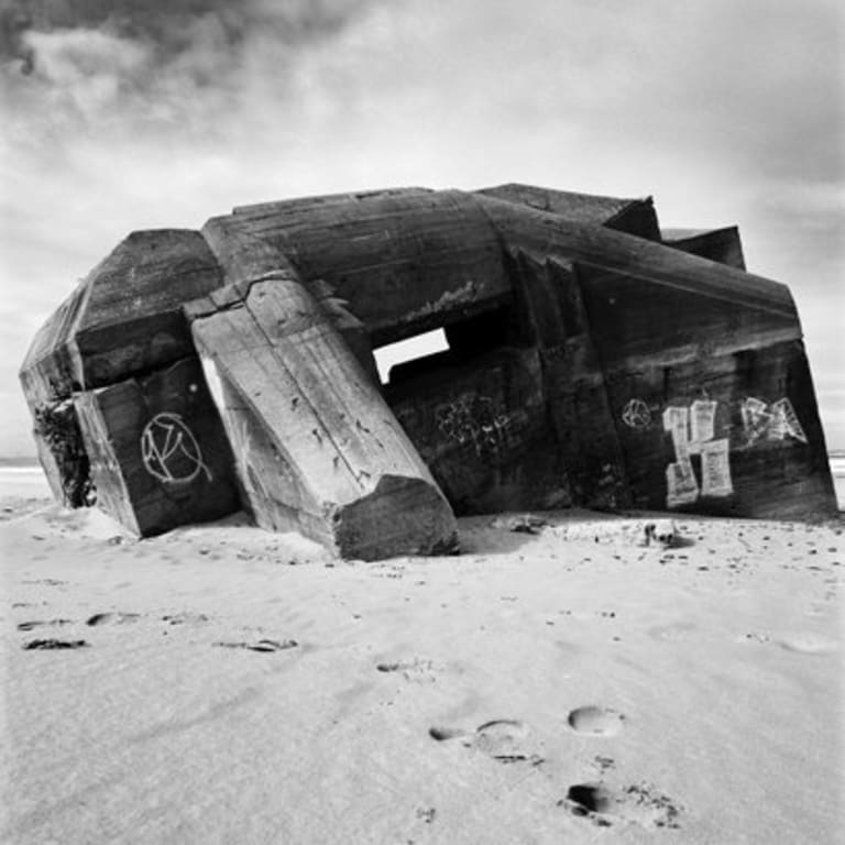 A concrete structure partly buried in the sand