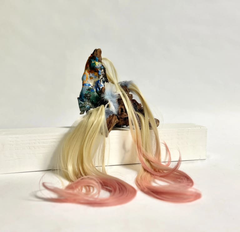 Mixed media sculpture with blonde and pink hair.