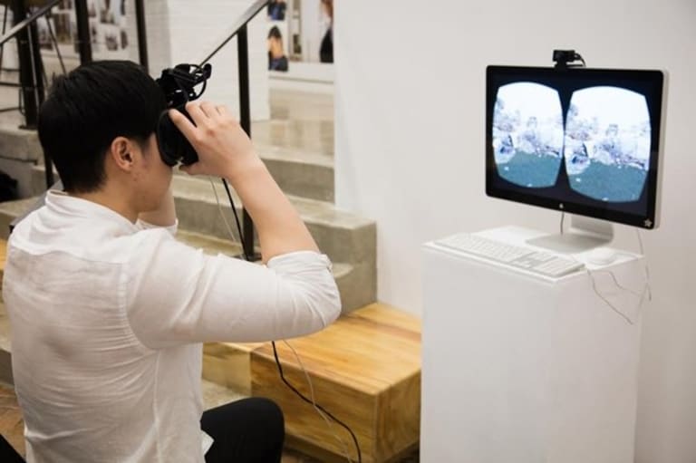 A young man dons a VR headset and looks at 3D imagery.