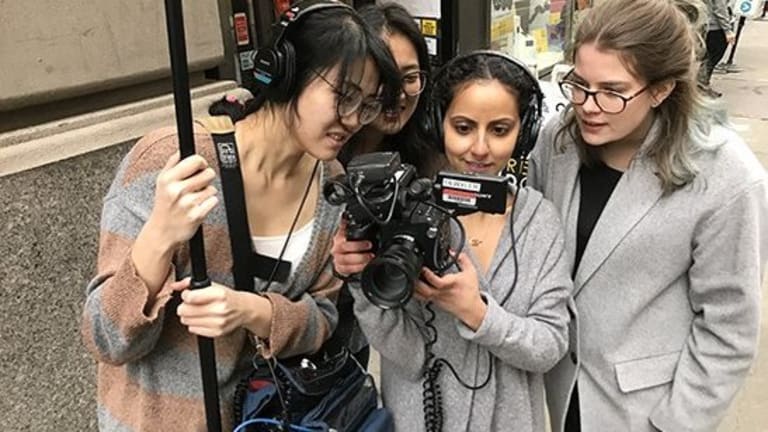 four female filmmakers on set, looking into the camera as they film a scene