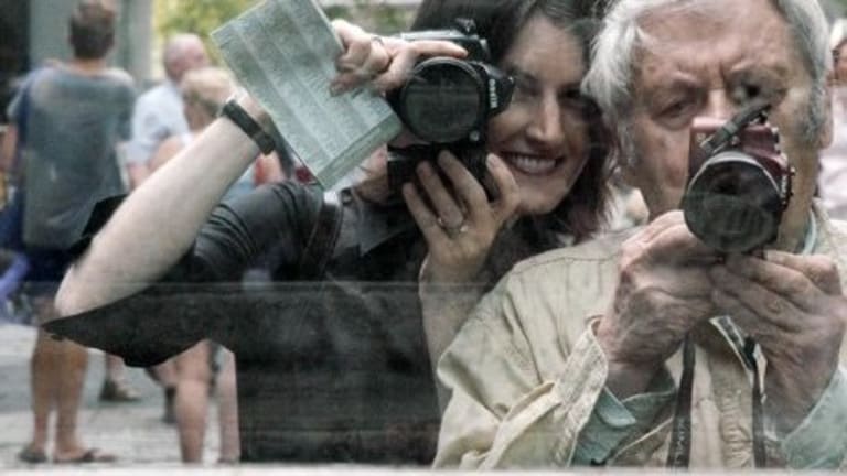 A woman and man holding cameras in their hands.