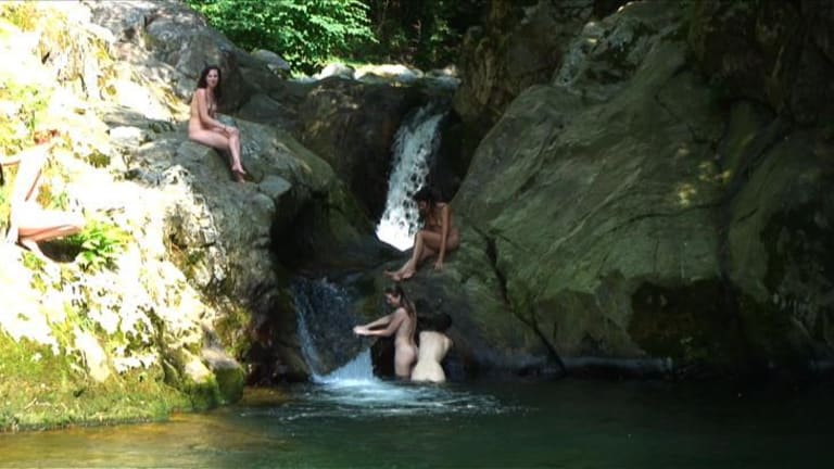 Women bathing at waterfall.