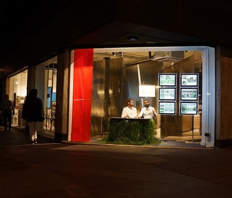 Two men in a window with six screens