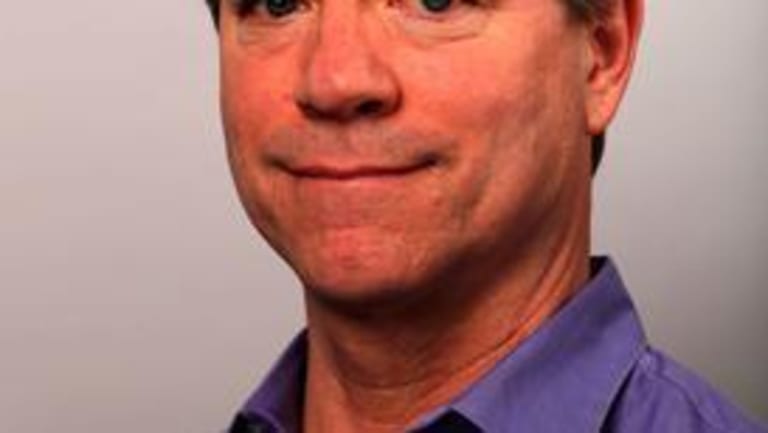 A white male wearing a purple shirt for a portrait.