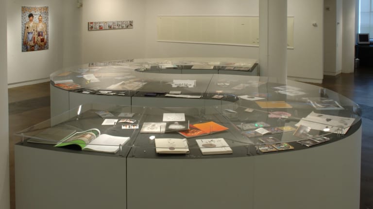 A curved counter, in the shape of an "S," displays books and prints within it. 