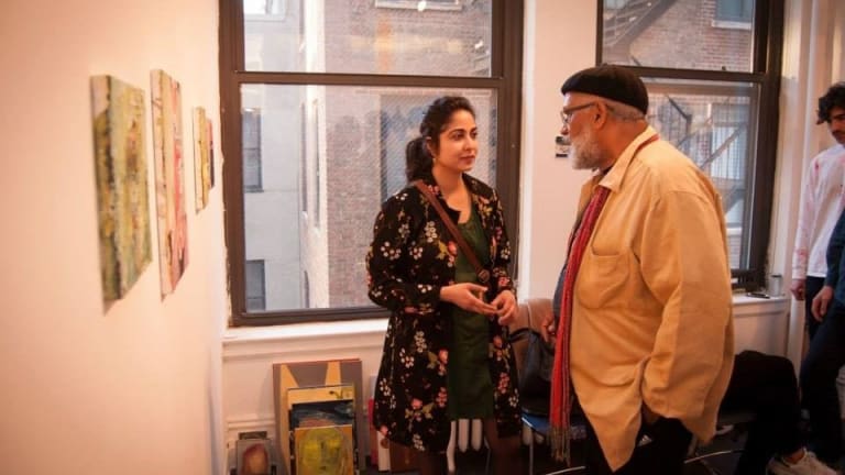 A man and woman have a discussion next to art hanging on the wall.