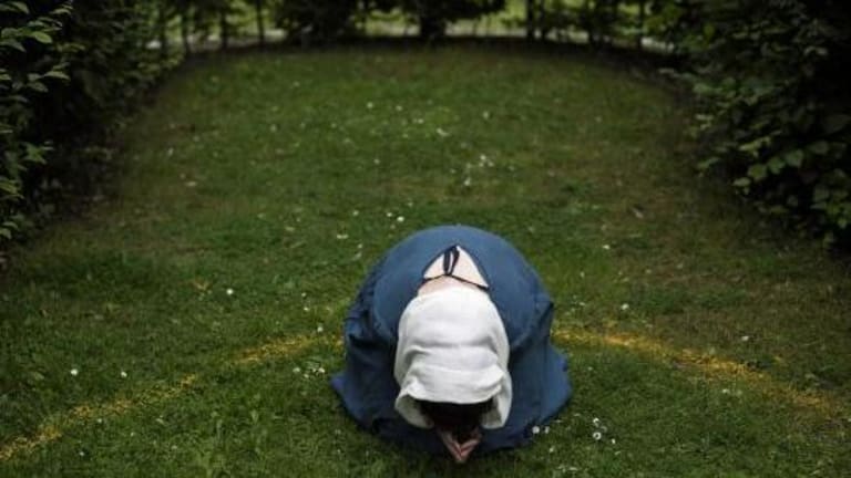 A woman kneels in a yellow bordered space of a garden.