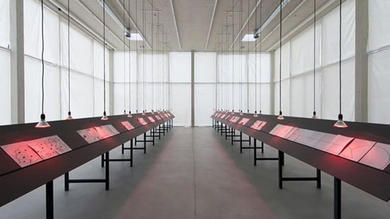 An art exhibition with several displays under red lights