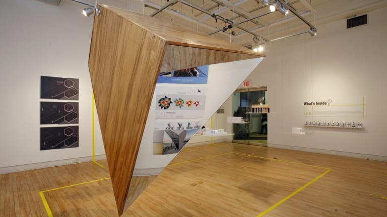 An art piece made of a triangular wood and mirrored prism suspended from the ceiling.