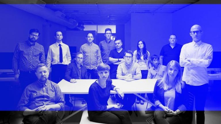 A blued over black and white photo of men and women sitting around a white table.