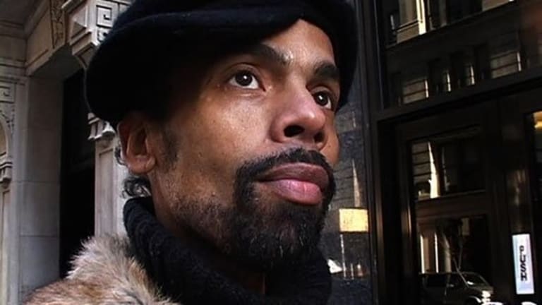 African American man with a goatee wearing a black hat. Man is wearing a fur collar.