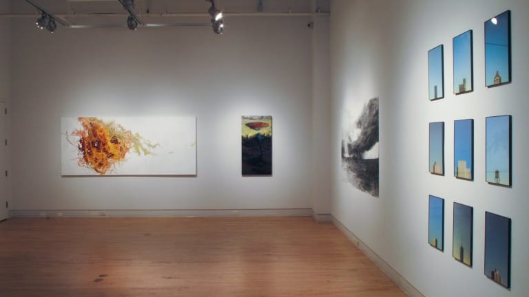 Artwork at a gallery with a wood floor and overhead lighting