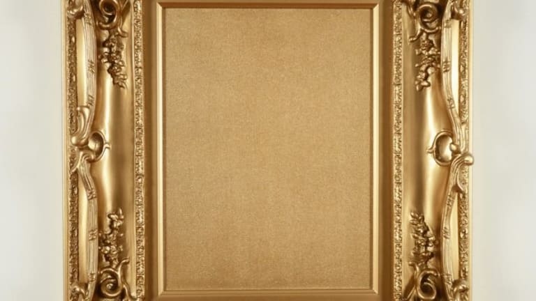 A gold picture frame with intricate design on the border.
