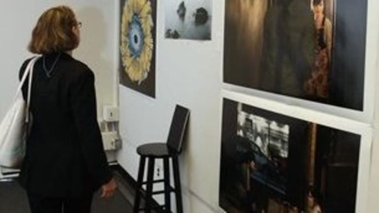 A woman looks at several pieces on the wall of a gallery.