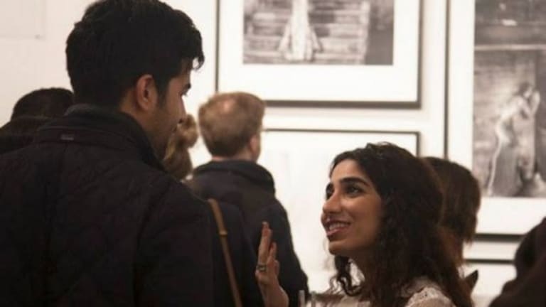 Girl is holding a jacket in his hand and speaking to a man