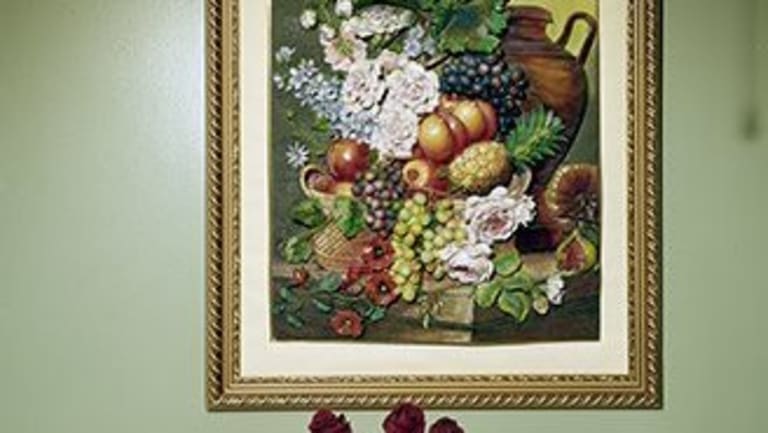 Oil painting of fruits on a green wall. A Gatorade bottle with flowers inside on the table.