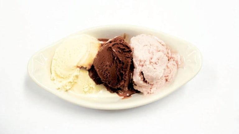 Three scoops of ice cream sit in a oblong bowl.