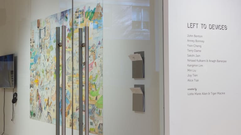View from right outside primary gallery space, with exhibition title and artist names applied to wall beside door.