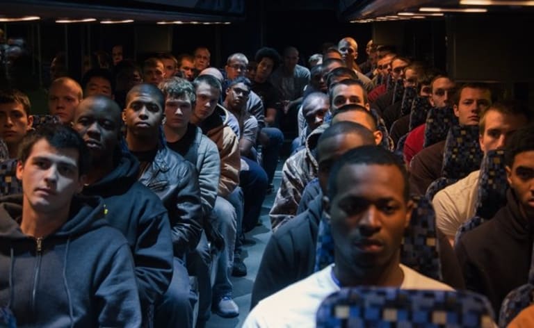 The interior of a bus filled with college aged men.